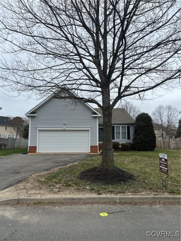 view of front of house with a garage, a front lawn, driveway, and fence