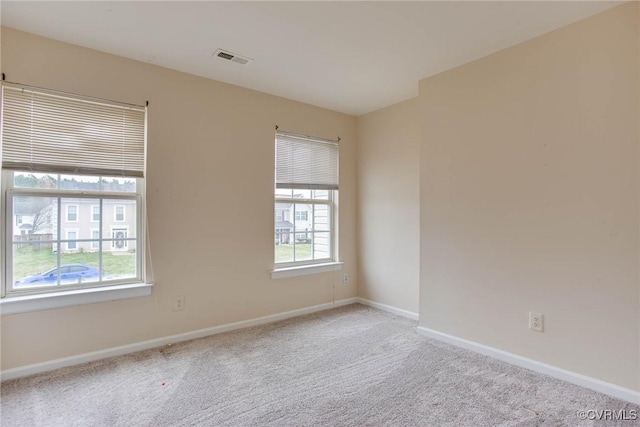 carpeted spare room featuring visible vents and baseboards