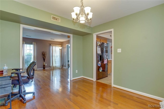 office space with an inviting chandelier, wood finished floors, visible vents, and baseboards