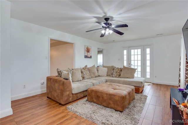 living room with light wood-style flooring, baseboards, and ceiling fan