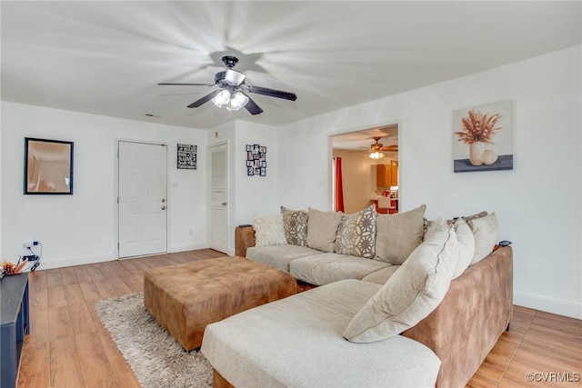 living area with a ceiling fan, baseboards, and light wood finished floors