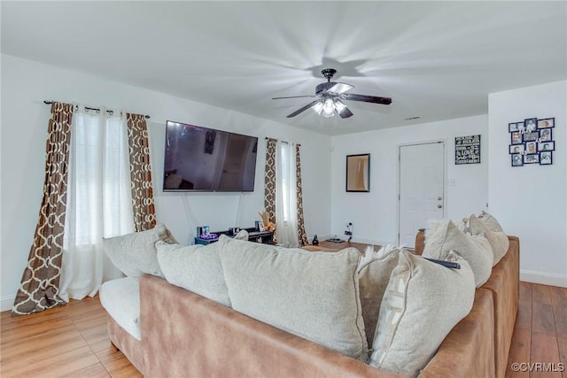 living room featuring wood finished floors, baseboards, and ceiling fan