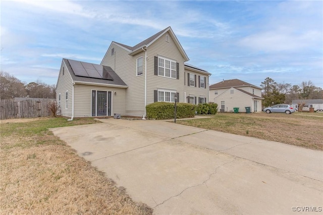 view of front of property with solar panels, a front yard, and fence