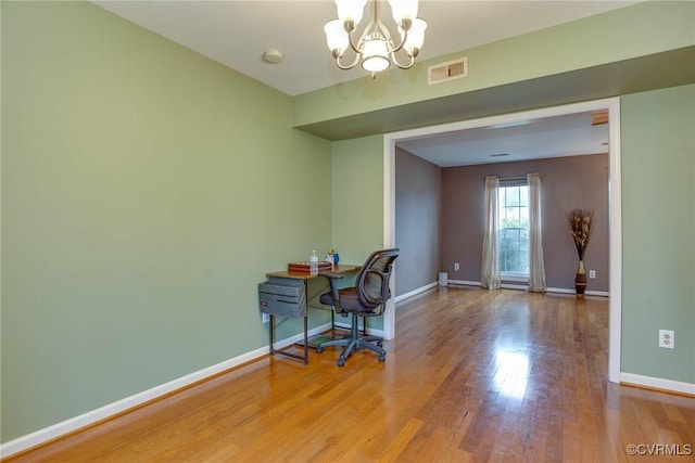 office area with a notable chandelier, wood finished floors, visible vents, and baseboards