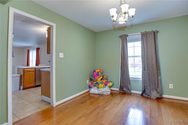 recreation room featuring a notable chandelier, baseboards, and light wood finished floors