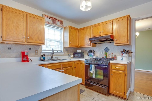 kitchen featuring backsplash, under cabinet range hood, light countertops, black appliances, and a sink