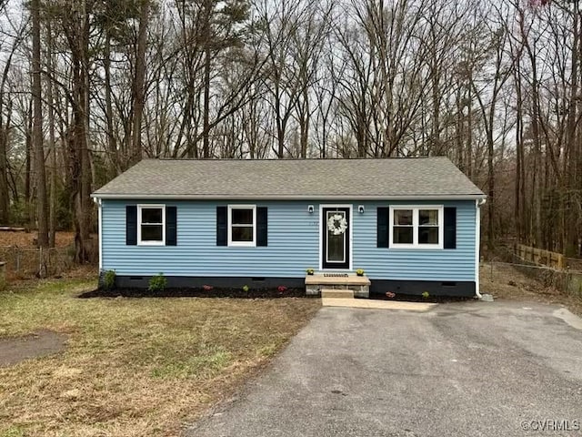 ranch-style home with crawl space, a shingled roof, a front lawn, and fence