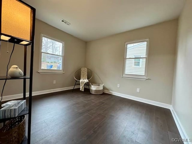 interior space featuring visible vents, baseboards, a healthy amount of sunlight, and dark wood-style flooring