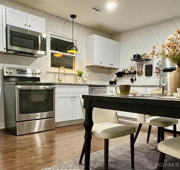 kitchen with stainless steel appliances, visible vents, dark wood-style floors, and white cabinets