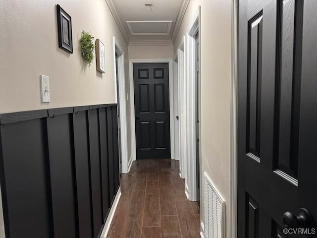 hall with a wainscoted wall, crown molding, dark wood-style floors, and visible vents