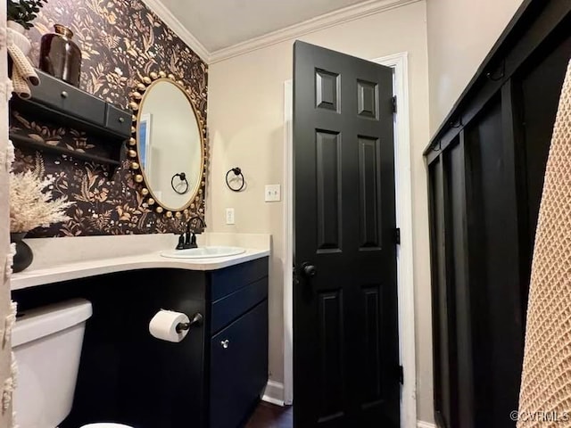 half bathroom with vanity, baseboards, wallpapered walls, ornamental molding, and toilet