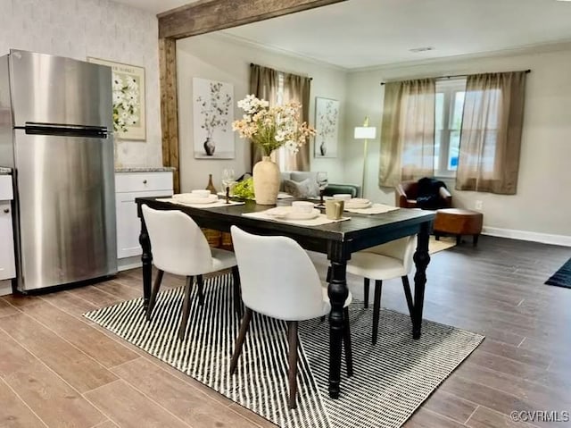 dining area featuring beamed ceiling, ornamental molding, baseboards, and wood finished floors