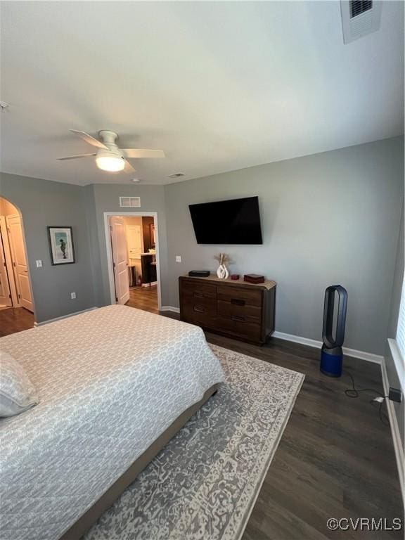 bedroom with dark wood-type flooring, baseboards, visible vents, and arched walkways