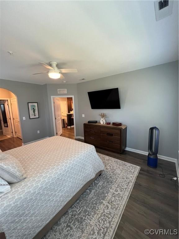 bedroom featuring dark wood finished floors, visible vents, arched walkways, and baseboards