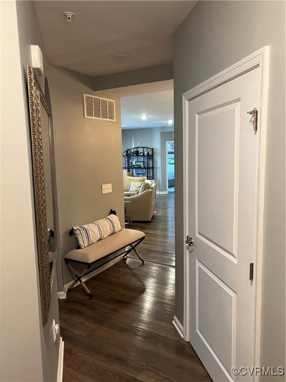 corridor featuring dark wood-type flooring, baseboards, and visible vents