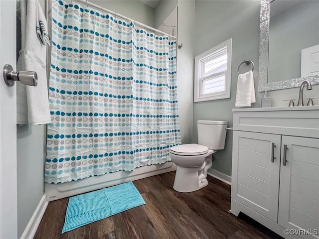 bathroom featuring toilet, wood finished floors, shower / tub combo, baseboards, and vanity