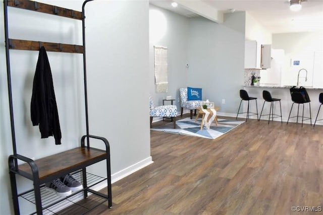 sitting room with beamed ceiling, baseboards, and wood finished floors