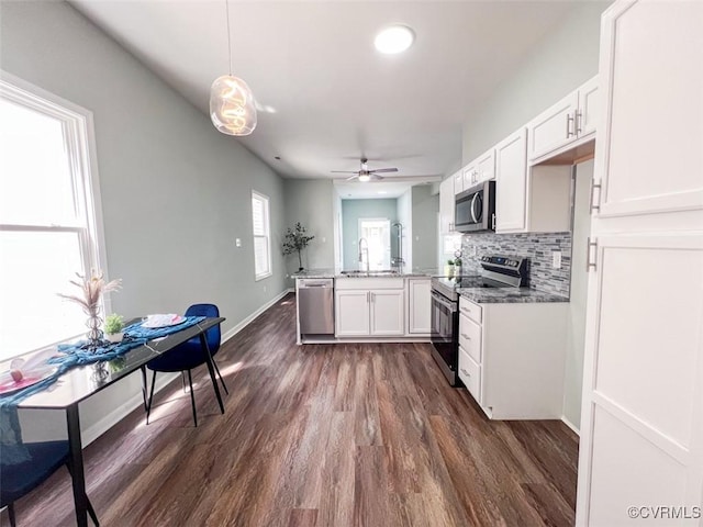 kitchen with a ceiling fan, stainless steel appliances, a peninsula, white cabinets, and decorative backsplash