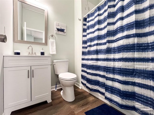 full bath featuring vanity, wood finished floors, baseboards, curtained shower, and toilet