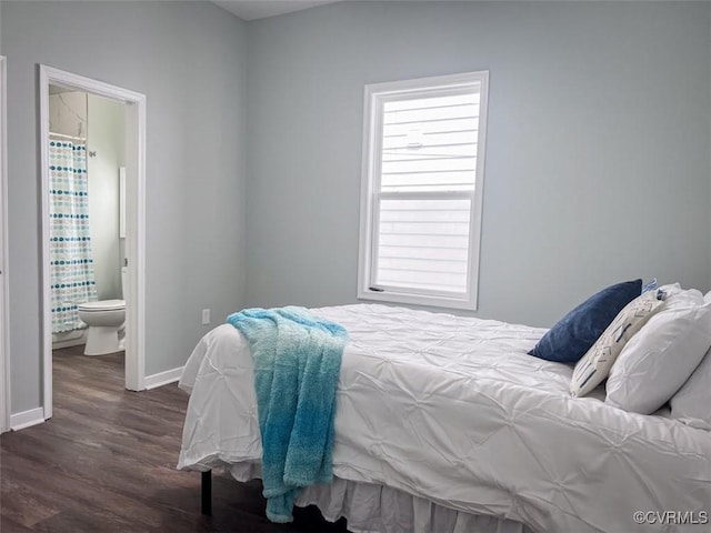 bedroom featuring ensuite bathroom, dark wood-type flooring, and baseboards