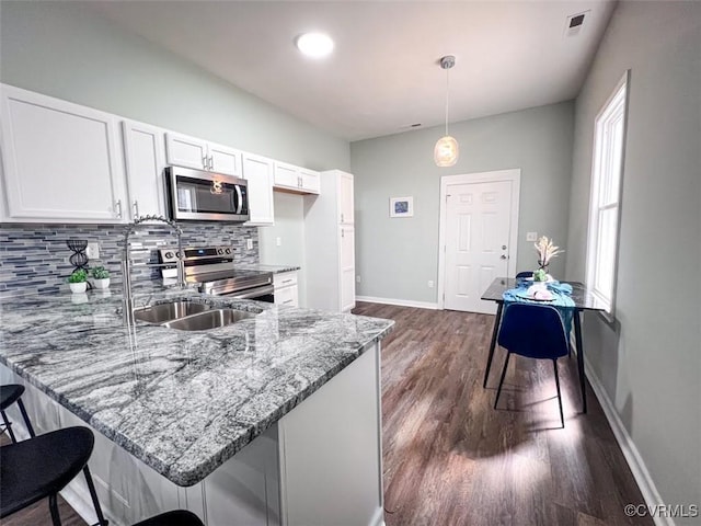 kitchen featuring white cabinetry, light stone countertops, appliances with stainless steel finishes, and a sink