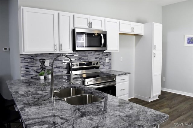 kitchen featuring dark stone countertops, backsplash, appliances with stainless steel finishes, and white cabinetry