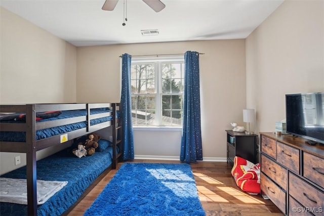 bedroom featuring baseboards, visible vents, a ceiling fan, and wood finished floors