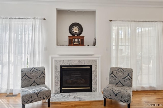 sitting room with visible vents, ornamental molding, wood finished floors, and a wealth of natural light