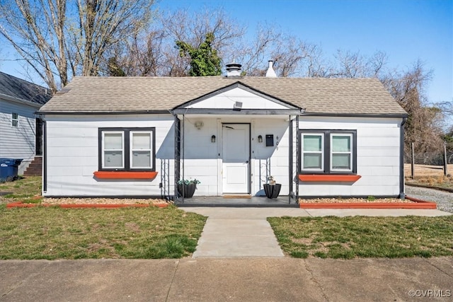 bungalow-style home with a shingled roof and a front yard