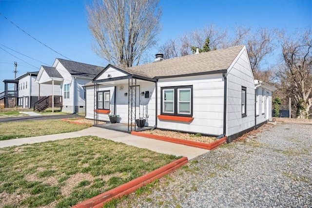 bungalow-style house with a front yard and a shingled roof