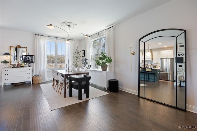 dining area with dark wood-style floors, arched walkways, and baseboards