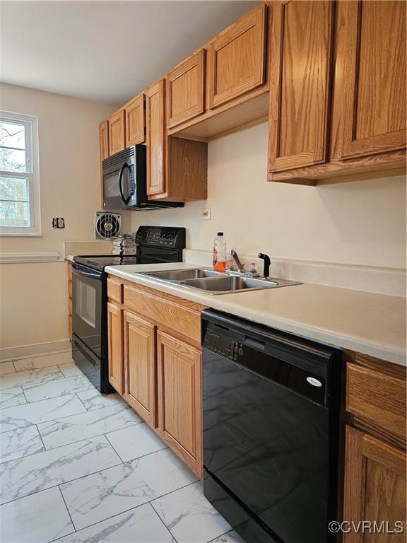 kitchen featuring baseboards, light countertops, marble finish floor, black appliances, and a sink