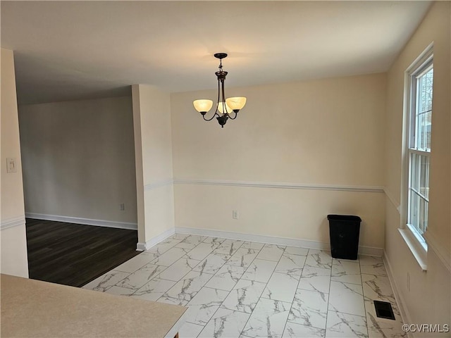 unfurnished room featuring a notable chandelier, visible vents, marble finish floor, and baseboards