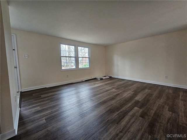 spare room with baseboards and dark wood finished floors