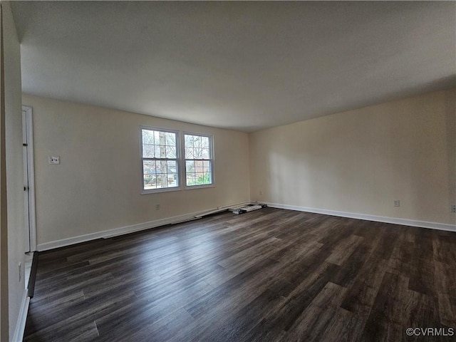 spare room with baseboards and dark wood finished floors