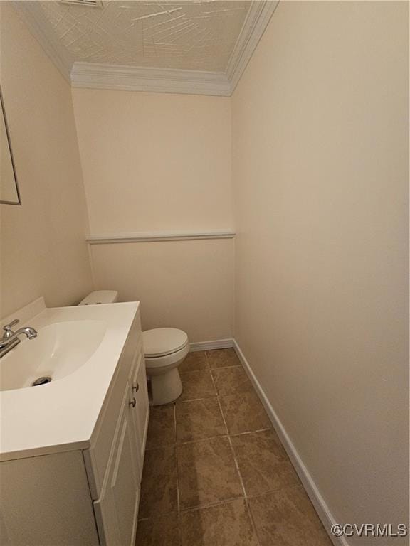 bathroom with vanity, crown molding, toilet, and baseboards