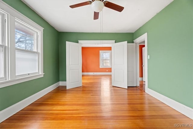 spare room with light wood-style flooring, a ceiling fan, and baseboards