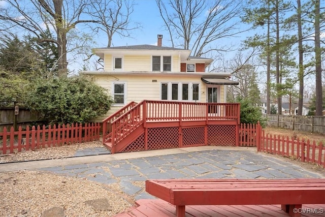 back of property featuring a wooden deck, fence private yard, a chimney, and a patio area