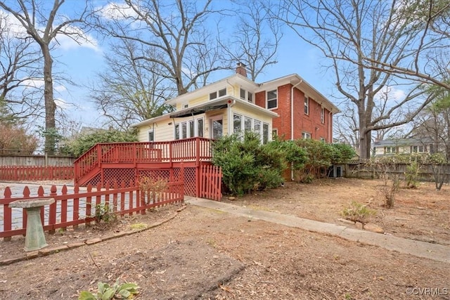 view of side of property with a wooden deck, fence, and a chimney