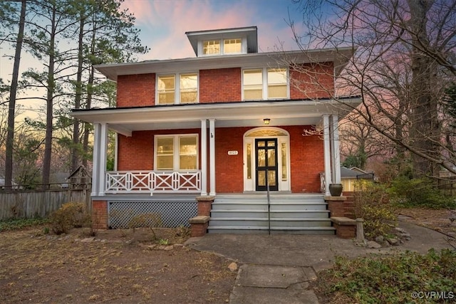 american foursquare style home featuring brick siding and a porch