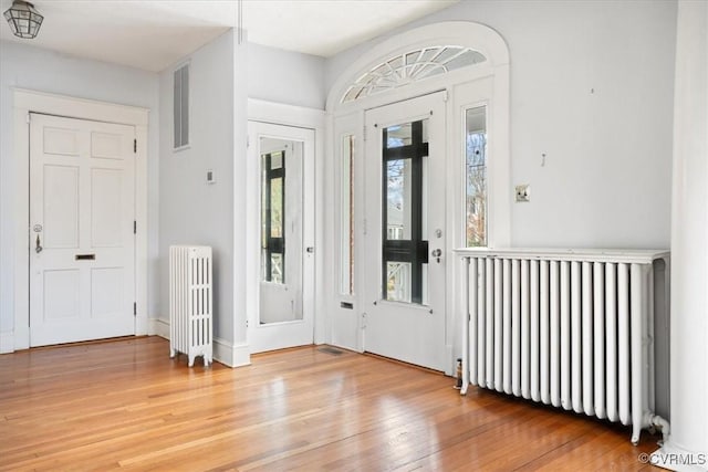 entrance foyer with radiator and wood finished floors