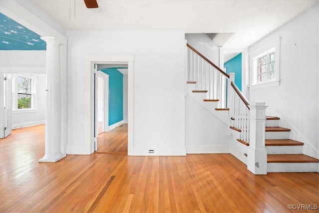 stairway with ceiling fan, decorative columns, baseboards, and hardwood / wood-style floors