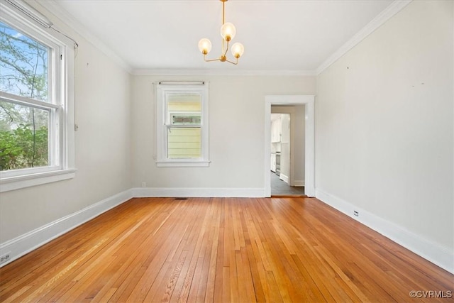 spare room with a chandelier, light wood-style flooring, crown molding, and baseboards