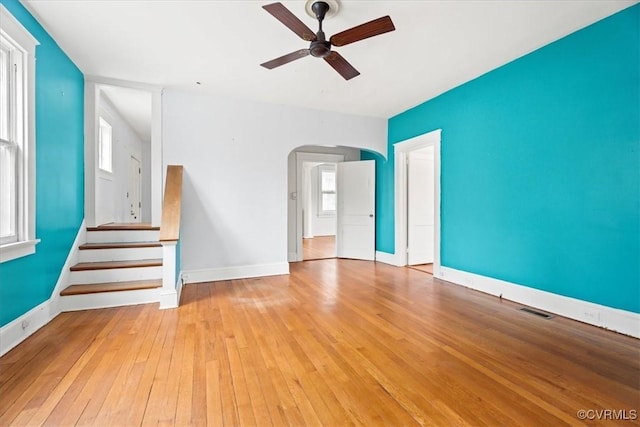 interior space featuring visible vents, wood-type flooring, arched walkways, baseboards, and ceiling fan