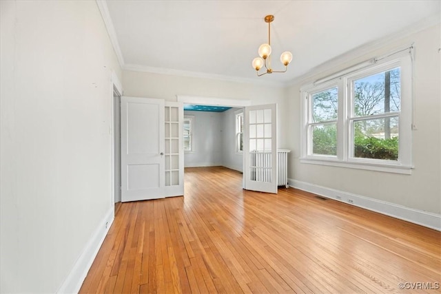 unfurnished room with light wood-style flooring, baseboards, ornamental molding, and french doors