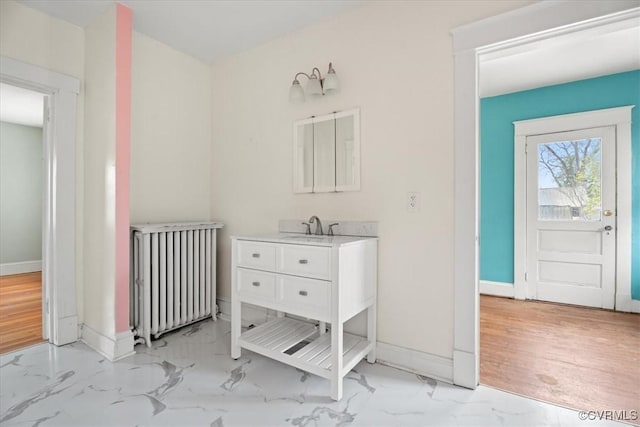 bathroom with baseboards, radiator, marble finish floor, and vanity