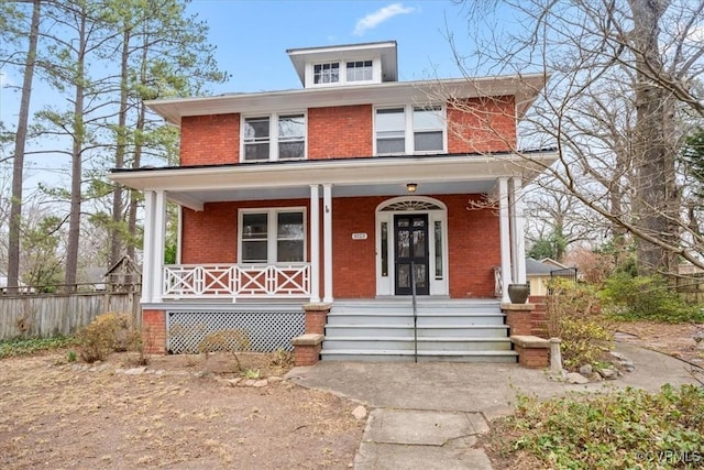 american foursquare style home with brick siding and covered porch