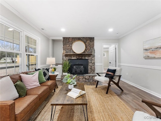 living area featuring visible vents, ornamental molding, wood finished floors, a stone fireplace, and baseboards