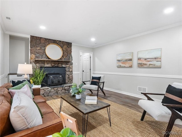 living room with a stone fireplace, wood finished floors, visible vents, and ornamental molding