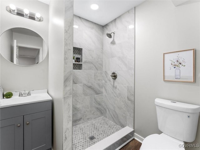 bathroom featuring vanity, toilet, and tiled shower